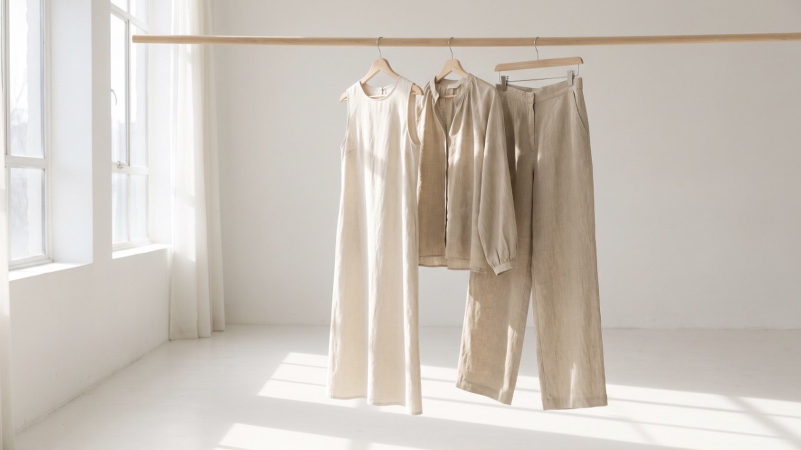 Ruhig arrangierte Leinenkleidung an einer Kleiderstange im Atelier