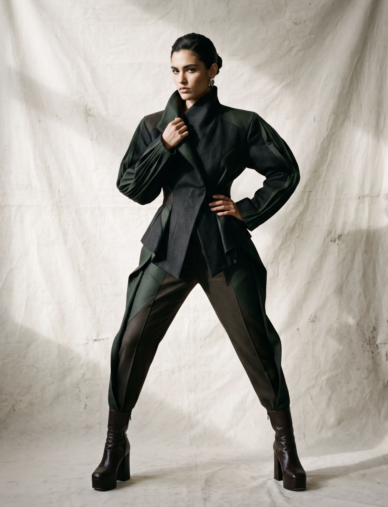 A model in an avant-garde tailored outfit against a studio backdrop